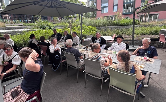 Eine Gruppe von Menschen in traditioneller Kleidung sitzt an einem Tisch im Freien und isst.